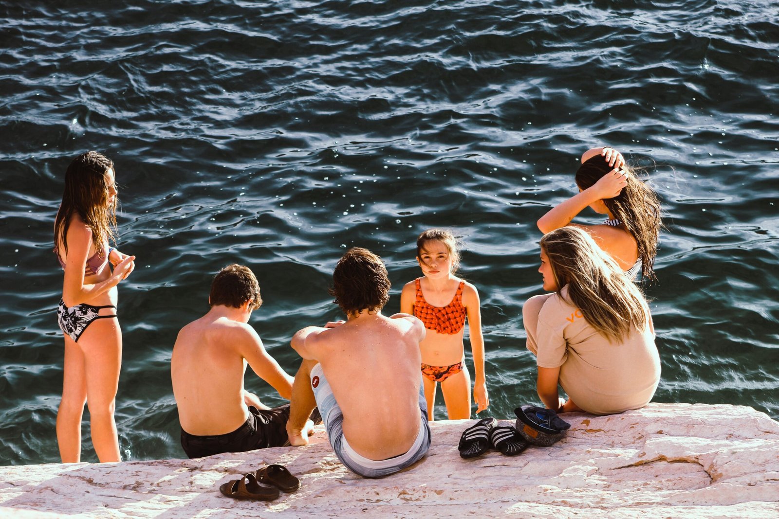 group of kids having a conversation near body of water